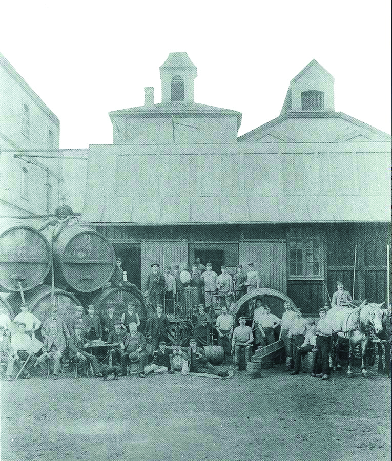 Historic French artisans working at a traditional upholstery and craftsmanship workshop in the early 20th century.
